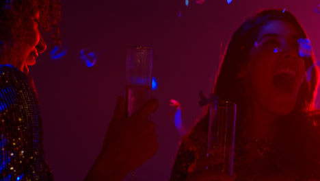 Close-Up-Of-Two-Women-In-Nightclub-Bar-Or-Disco-Dancing-And-Drinking-Alcohol-With-Paper-Confetti-1